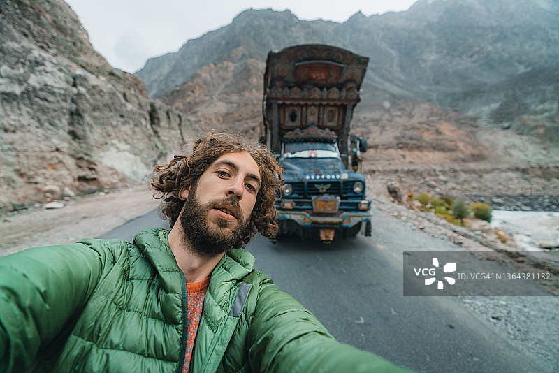 以色彩鲜艳的巴基斯坦卡车为背景的男人自拍照图片素材