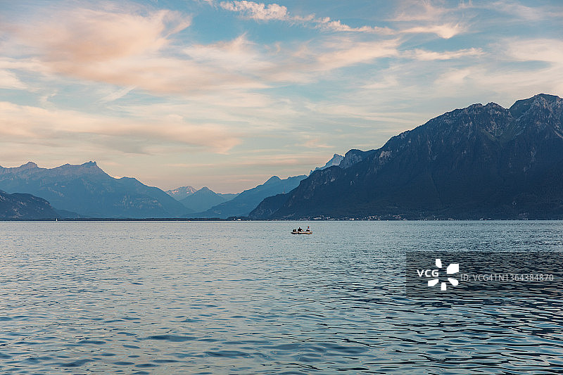 男人和女人在船上欣赏日落时的日内瓦湖和瑞士阿尔卑斯山图片素材