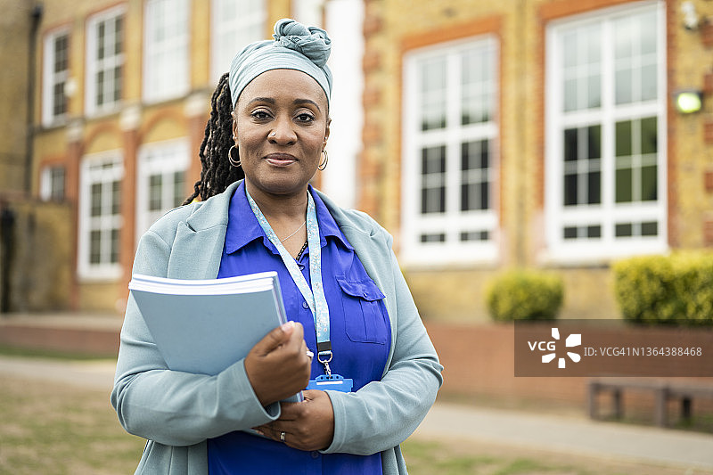 户外手持考试手册的黑人女教师图片素材