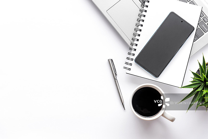 配有智能手机、笔记本、咖啡和笔记本电脑的办公室桌子图片素材