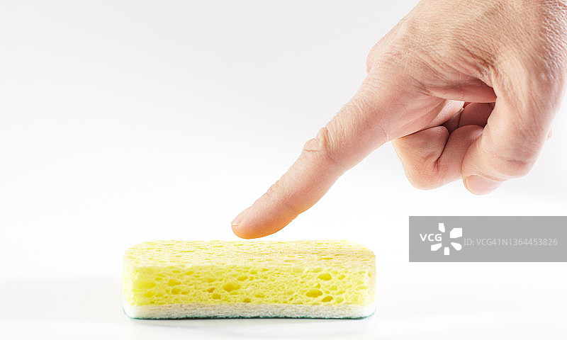 手指向黄色洗碗海绵的表面图片素材