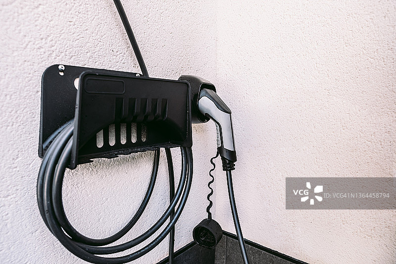 车库外电动汽车充电插座细节：电动汽车充电、可再生能源、可持续性和交通运输概念图片素材