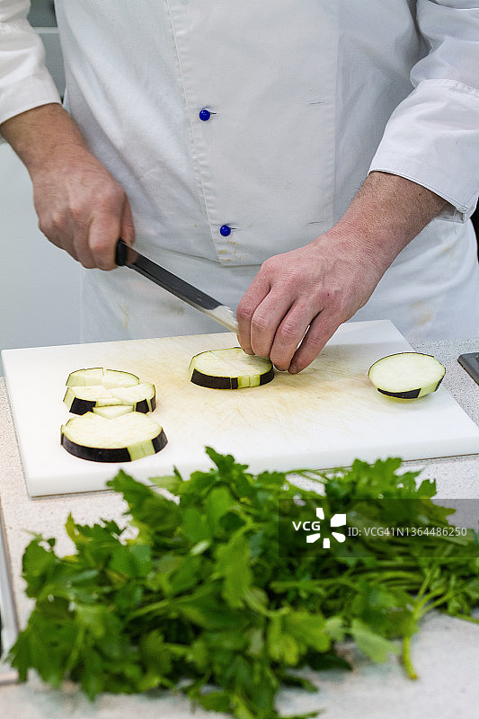 专业餐厅厨房里的厨师：切蔬菜图片素材