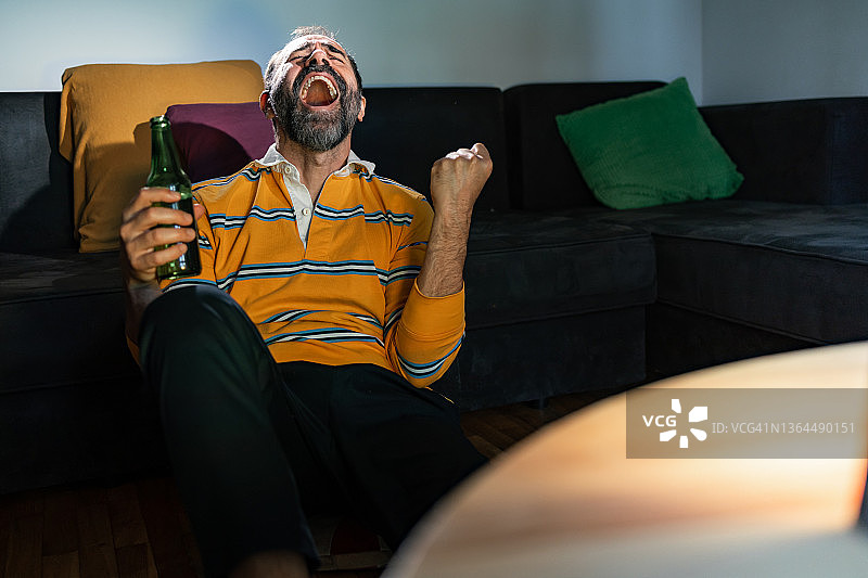 中年男人在家看电视上的体育直播图片素材