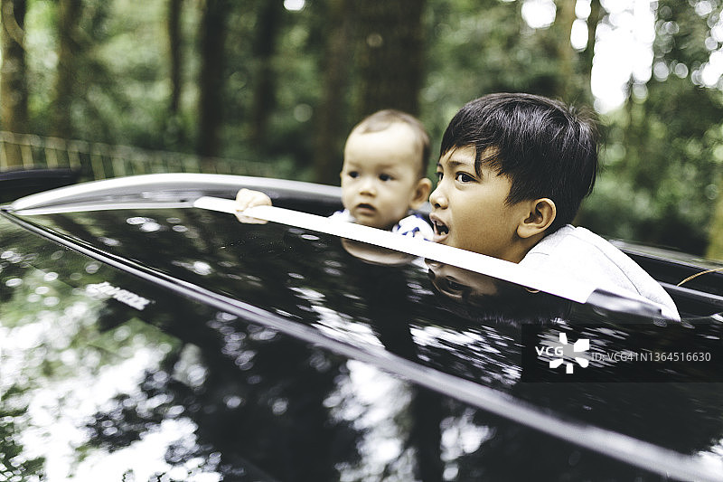 兄弟和弟弟从汽车天窗往外看图片素材