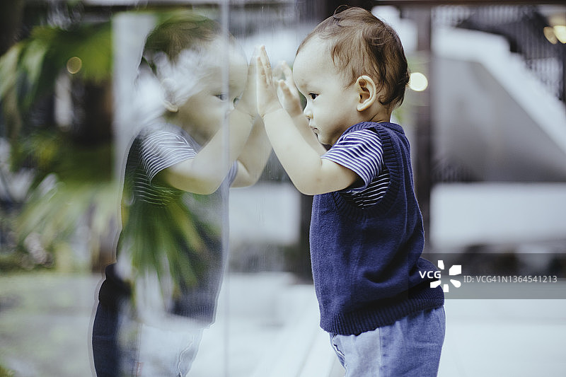 宝宝看着玻璃门外图片素材