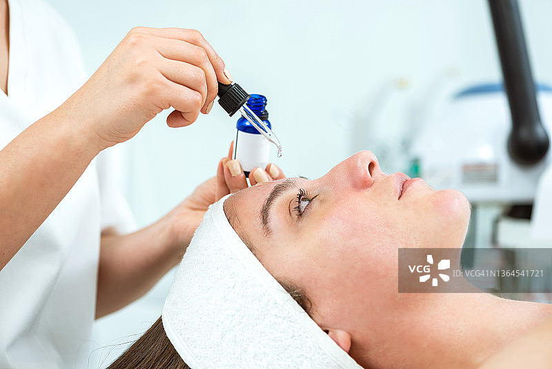 美容师将美容精华滴在女士脸上图片素材