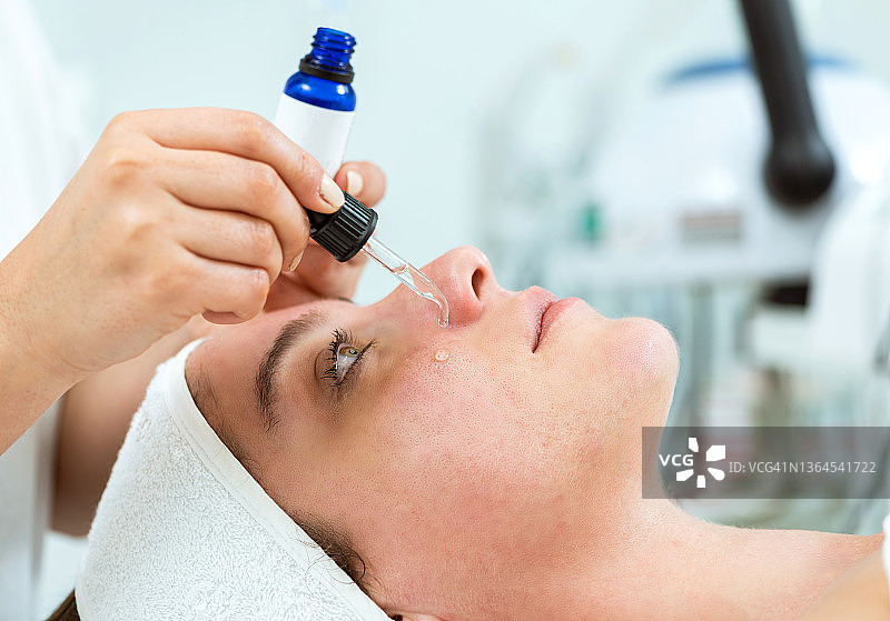 美容师将美容精华滴在女士脸上图片素材