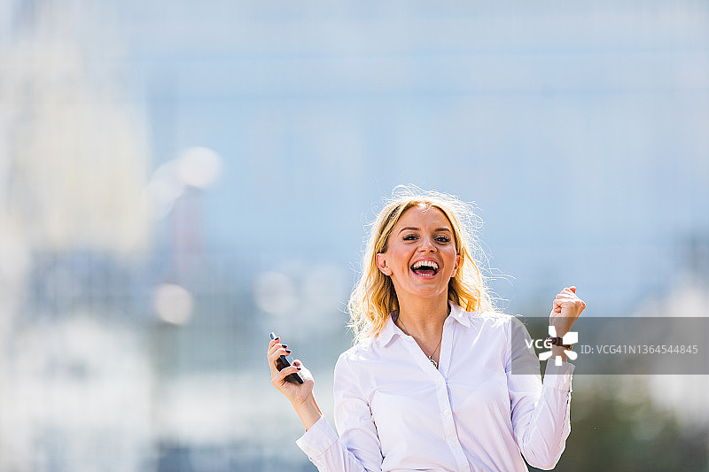 在城市里庆祝好消息的快乐女商人图片素材