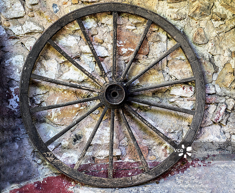 古老的木制车轮靠在乡村石墙上图片素材