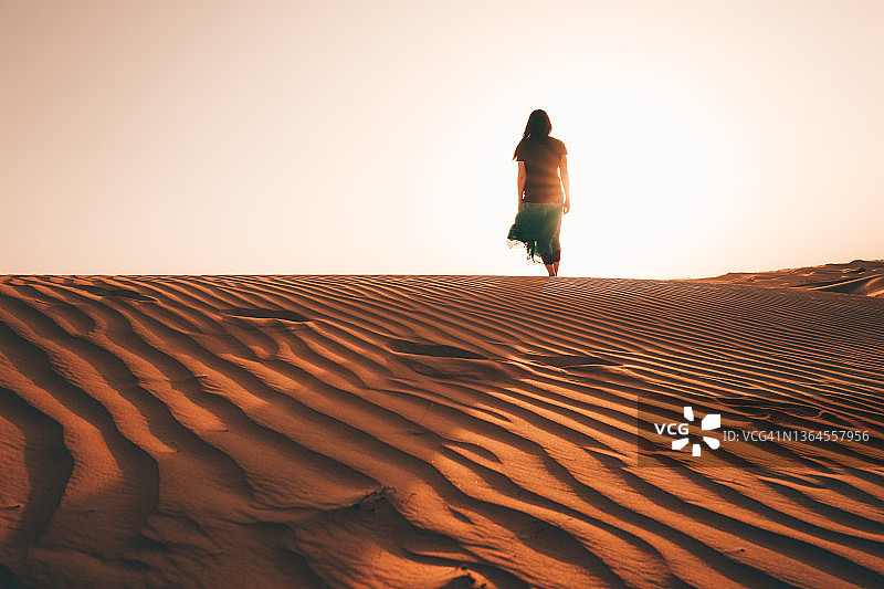 女人走向金色时段沙丘上的日落图片素材