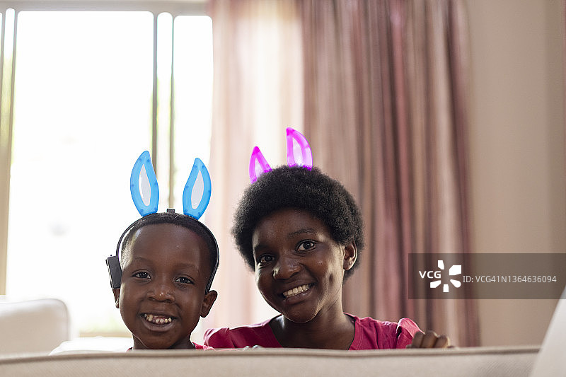 姐弟俩戴着复活节兔子耳朵，在沙发上玩耍图片素材