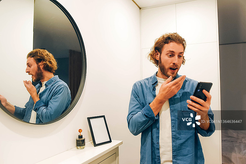 惊讶地看着手机的络腮胡男人图片素材