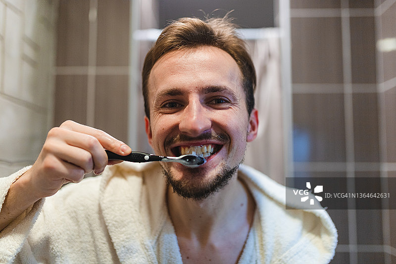 年轻男子身穿浴袍在浴室刷牙的特写图片素材