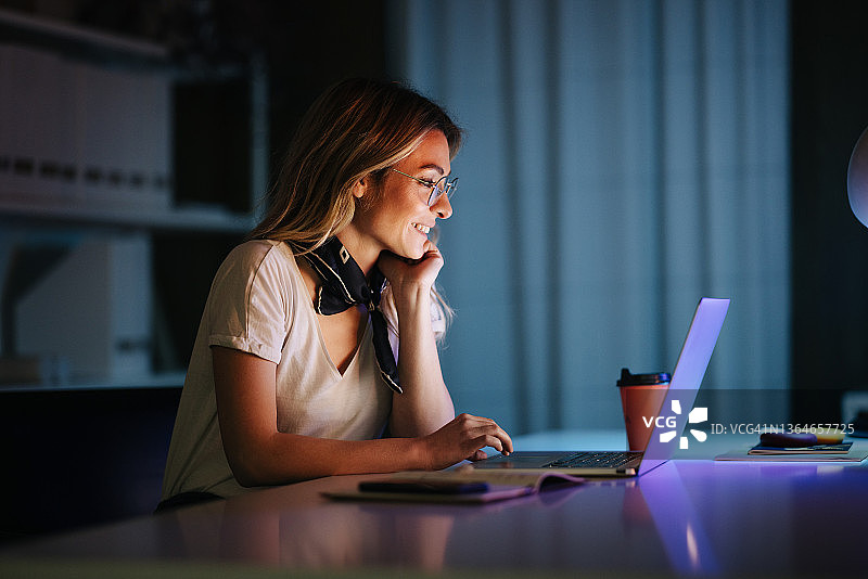 在办公室用笔记本电脑工作到深夜的美丽女商人图片素材