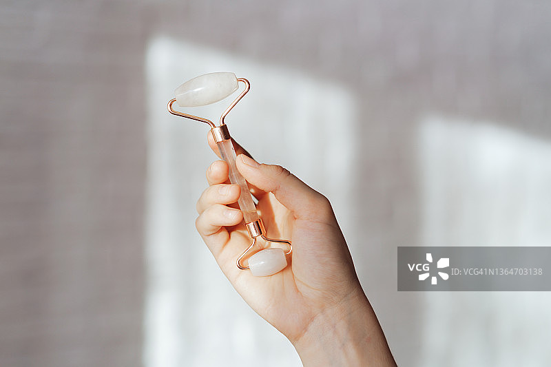 浅色背景前，手持双面石滚轮图片素材