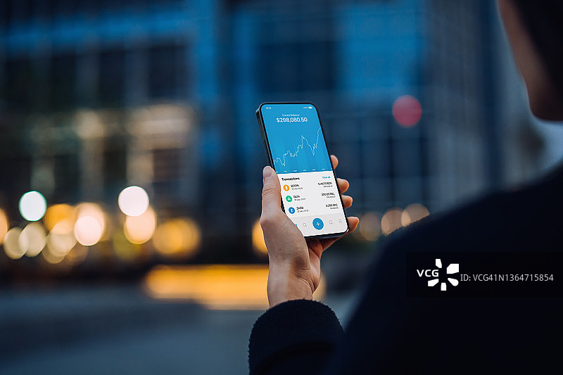 亚洲女性在城市街道用手机操作NFT投资钱包，从事区块链技术、加密货币数字资产交易图片素材