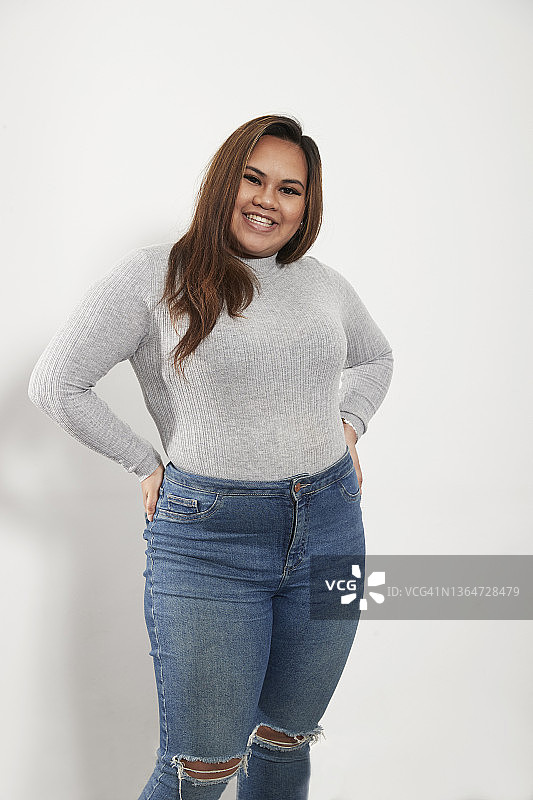 穿着毛衣和牛仔裤的自信年轻女人图片素材