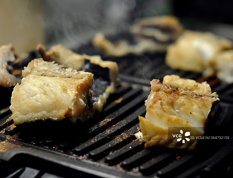 烤架上烤鳕鱼块特写，背景虚化图片素材