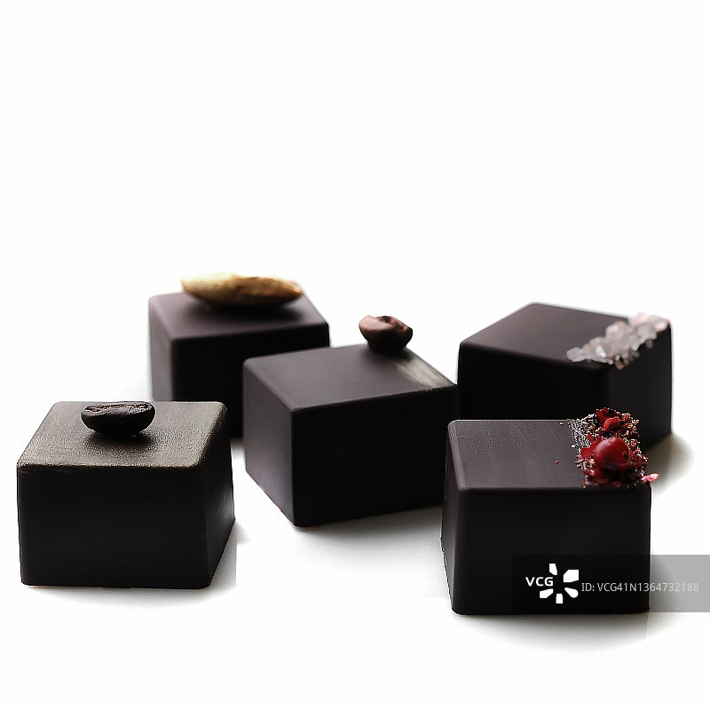 什锦方形黑巧克力糖果，艺术设计侧视白色背景极简风格特写。选择性聚焦图片素材