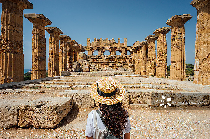 戴着帽子，欣赏西西里岛古老寺庙的女子背影图片素材