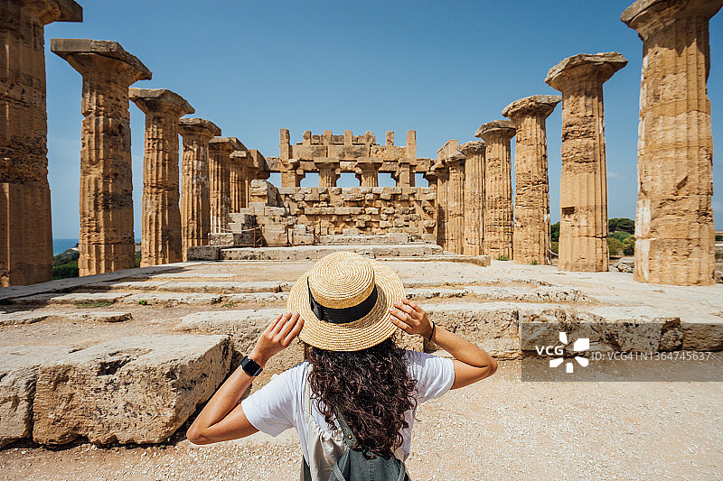 戴着帽子，欣赏西西里岛古老寺庙的女子背影图片素材