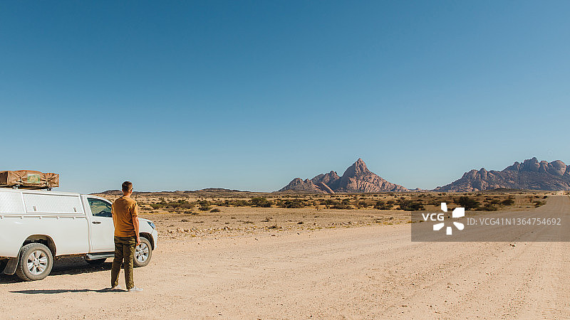 男人在纳米比亚的风景中漫步，房车相伴图片素材
