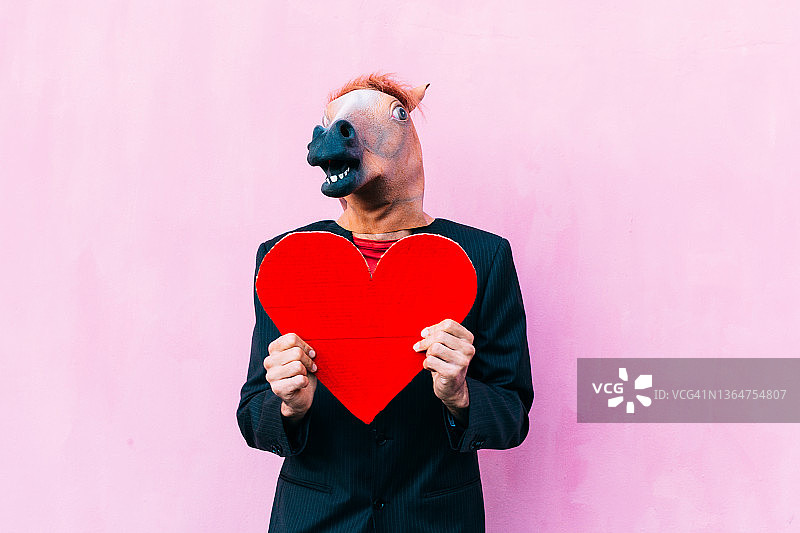 戴着马头面具，手捧红心的西装男人图片素材