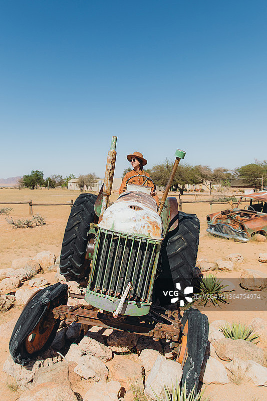 戴帽女人坐在纳米比亚沙漠中废弃的旧车里图片素材