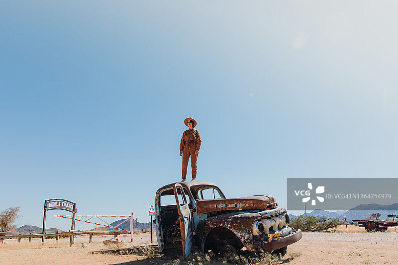 戴帽女人坐在纳米比亚沙漠中废弃的旧车里图片素材