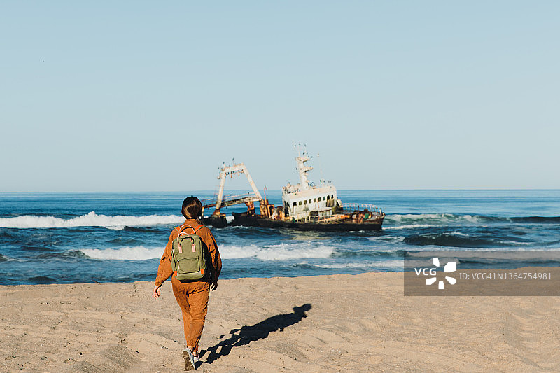女背包客在骷髅海岸观赏沉船美景图片素材
