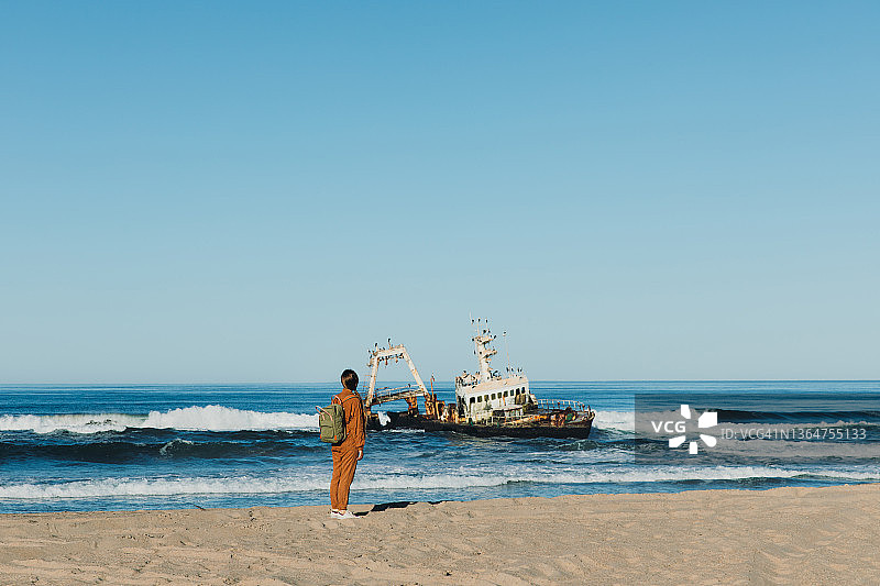 女背包客在骷髅海岸观赏沉船美景图片素材