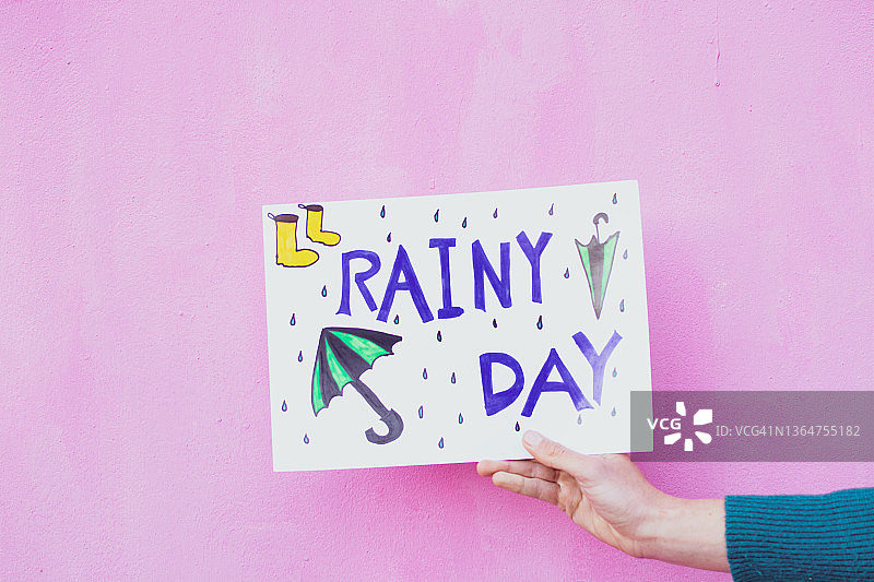 手持写着“雨天”的标牌图片素材