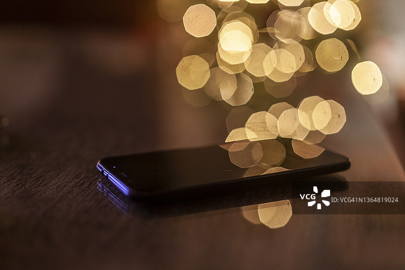 玻璃桌上的手机，背景是西班牙安达卢西亚哈恩省的圣诞树灯光图片素材