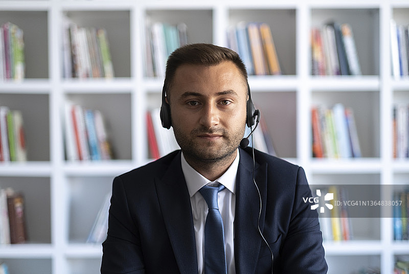 微笑的商务人士戴着耳机在笔记本电脑上进行视频会议图片素材