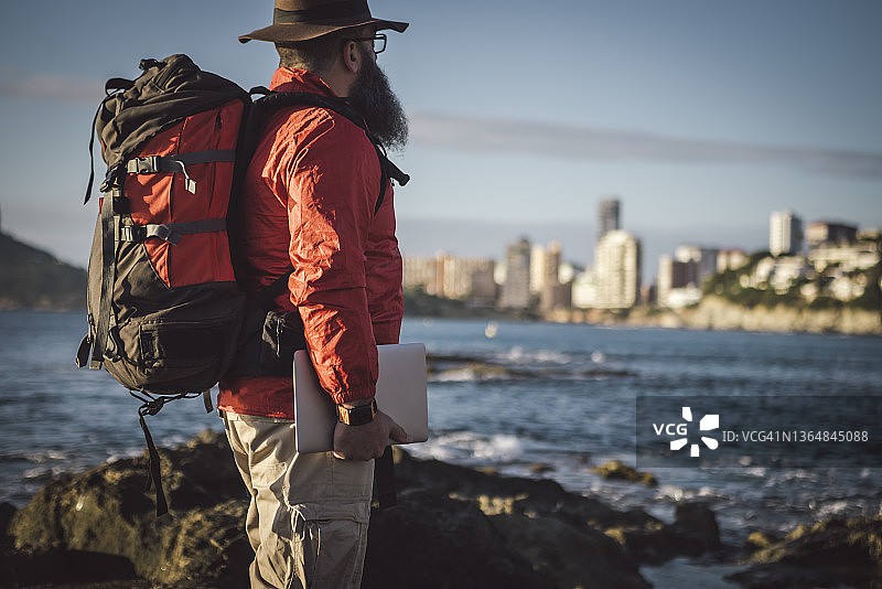 数字游民在海上用笔记本电脑工作，城市背景图片素材