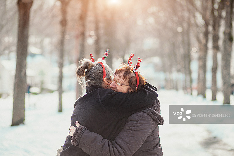 两位年长的妇女在圣诞节期间在户外跳舞和拥抱图片素材