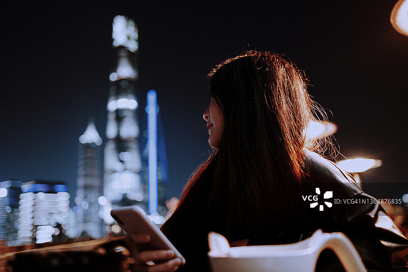 自信的年轻亚裔女性在上海的屋顶上使用智能手机图片素材