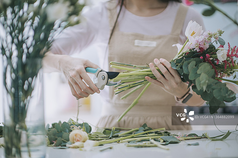 亚洲女花艺师在家中厨房修剪花束，经营小本生意图片素材