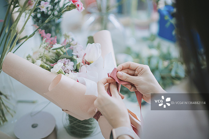 亚洲女花艺师在家包装花束特写图片素材
