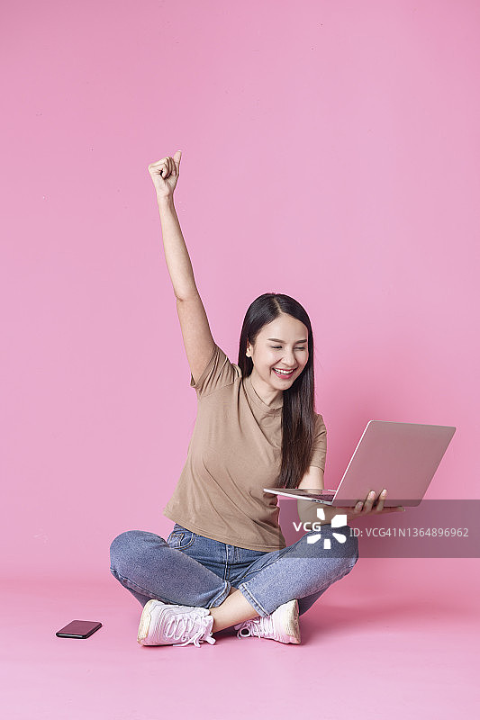 快乐的女商人拿着手机和信用卡，背景为粉色图片素材