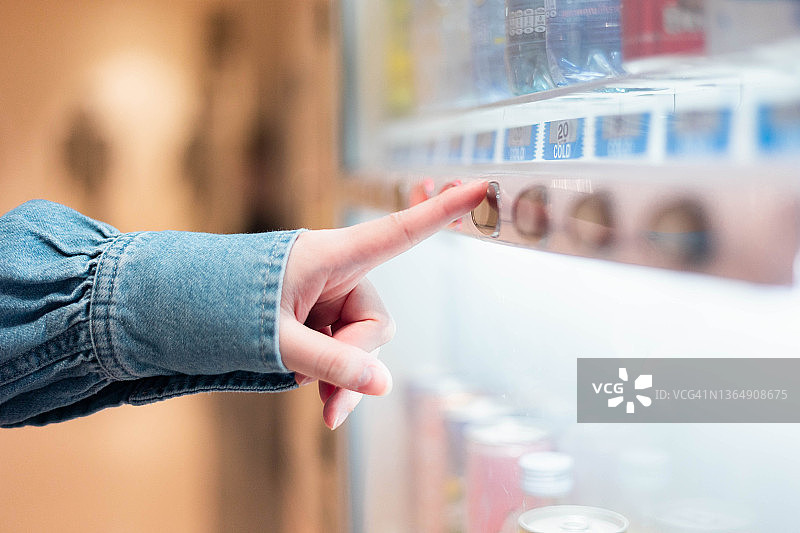 在自动售货机购买清凉饮料的女子局部特写图片素材