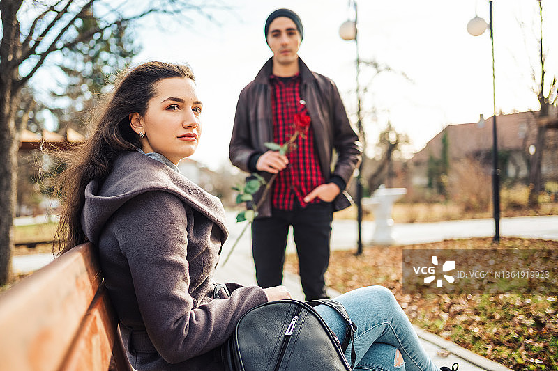 在公园里向女朋友求爱的年轻男人，手持红玫瑰图片素材