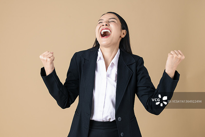 影棚拍摄：欢呼雀跃的女商人举起双臂握拳庆祝好消息图片素材