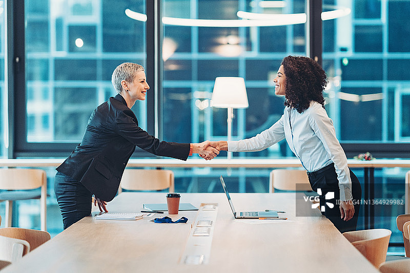 两位女商人在桌子旁握手图片素材