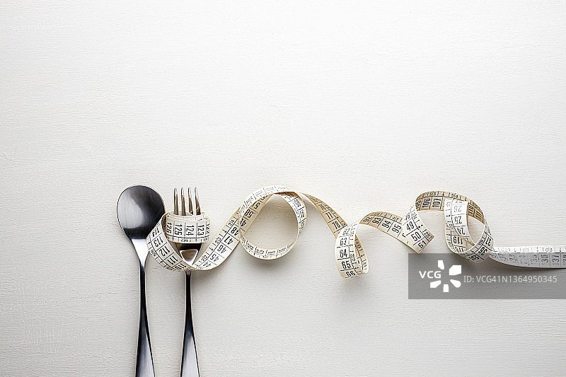 饮食概念：白色背景上的卷尺、勺子和叉子图片素材