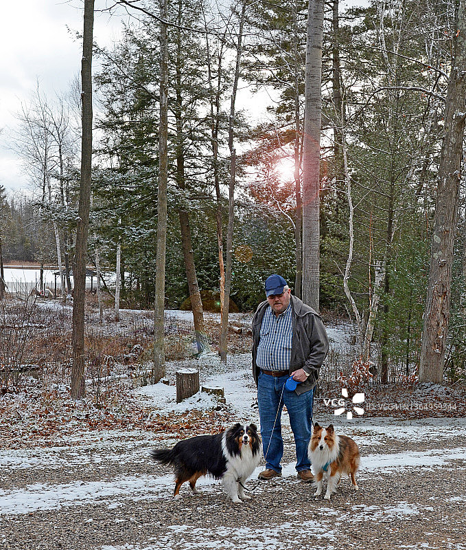 冬天里遛狗的年长者男人图片素材