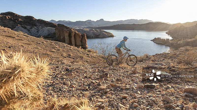 日出时分，女人在沙漠中骑山地自行车图片素材
