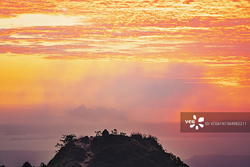 粉色雾气日落时分的海上山顶图片素材