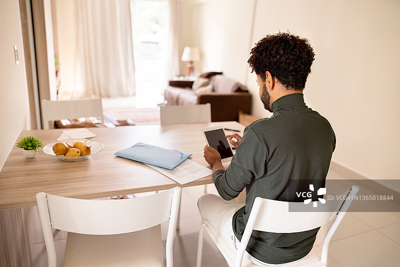 在家远程办公，使用平板电脑的年轻男人图片素材